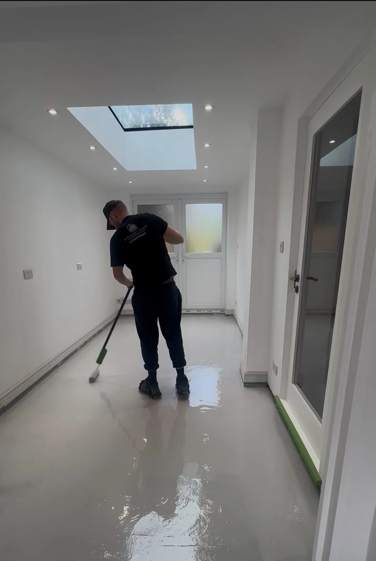 Michael Delaney applying a resin floor with a roller in a bright interior