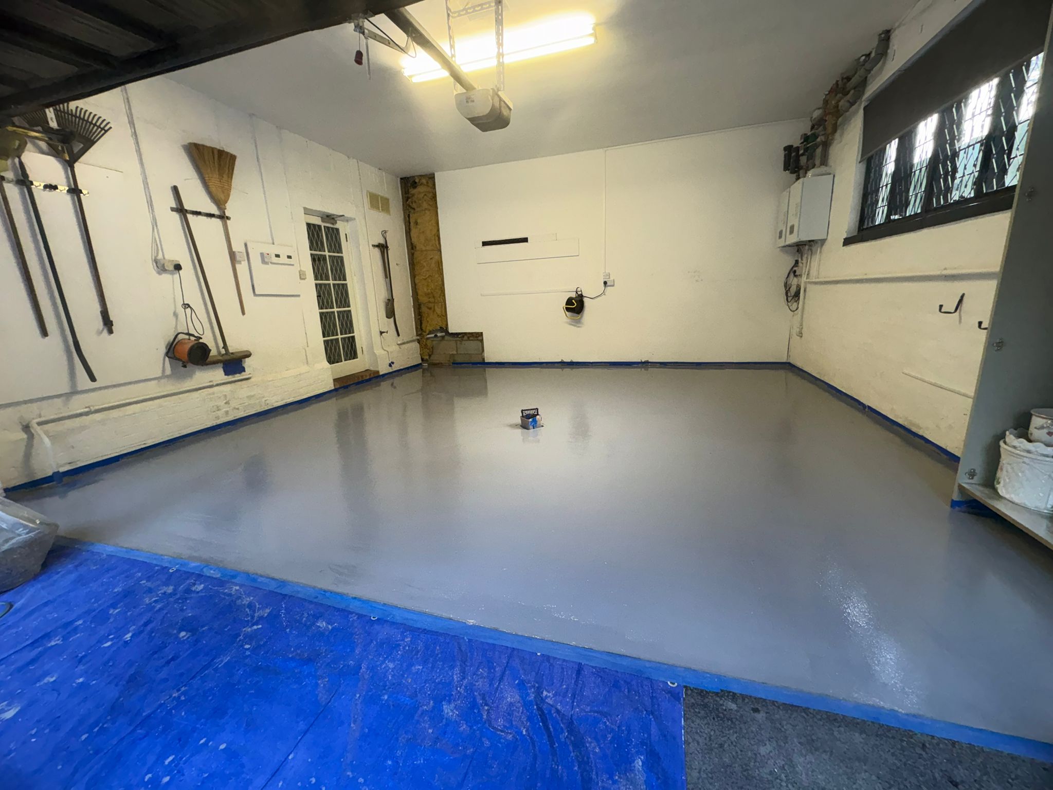 Smooth grey resin base coat across the garage floor