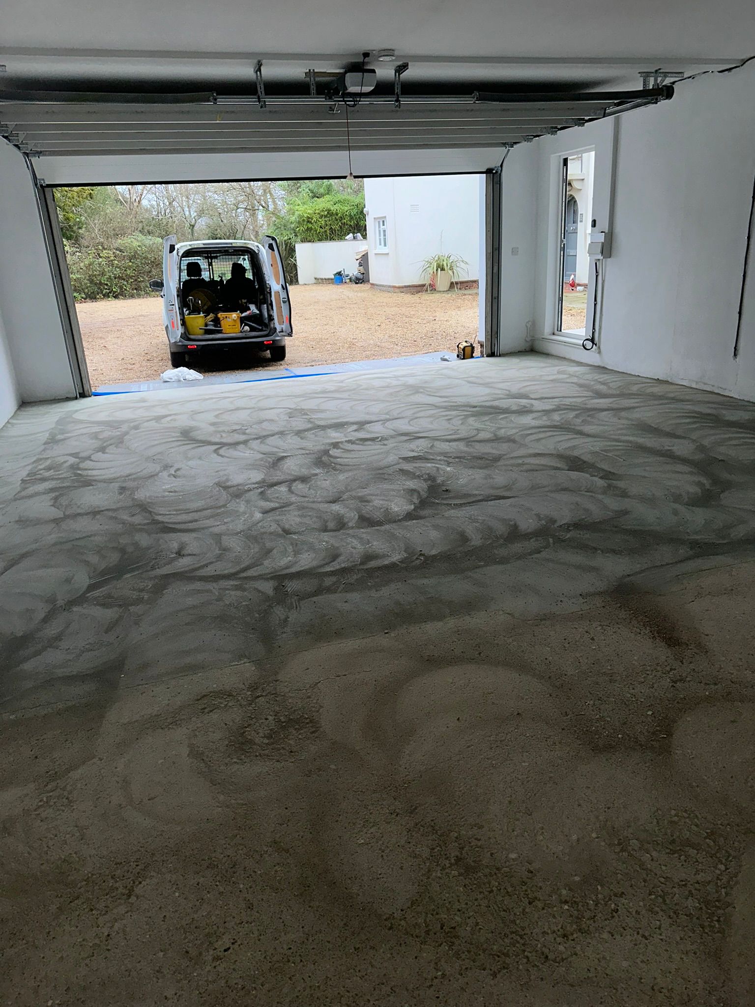 Bare concrete across the long garage before coating