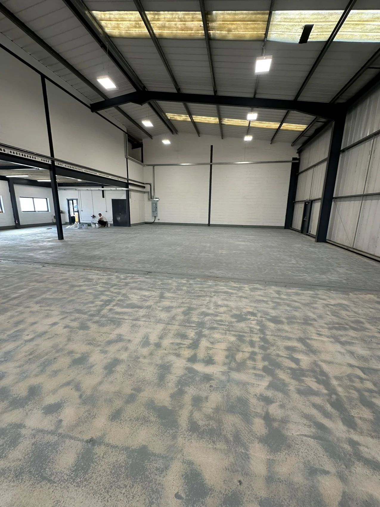 Warehouse floor before coating, with preparation visible around the steel columns